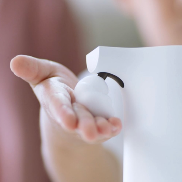 Baby's hand holding a small white object with a black mark against a blurred background