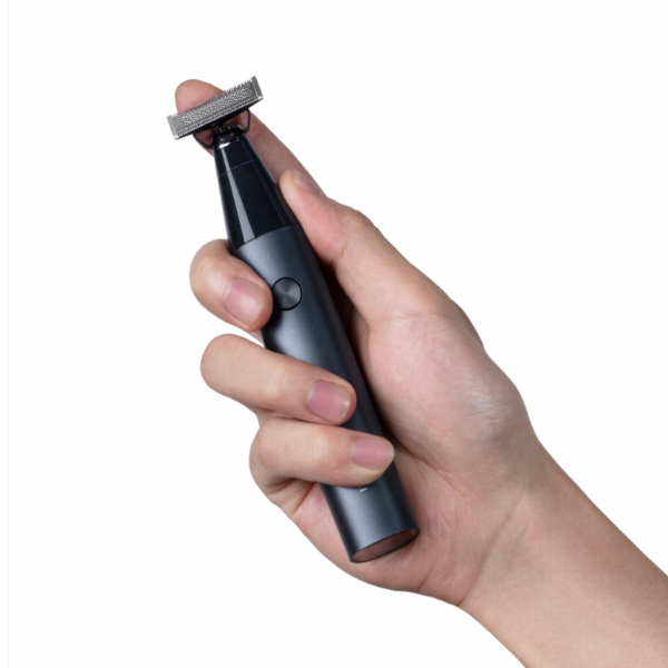 Hand holding a black electric razor on a white background