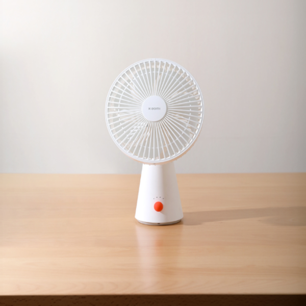 Small white fan on a wooden surface with a plain background