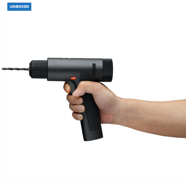 Hand holding a black handheld drill on a white background with 'UNBOXED' branding.