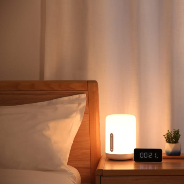 Bedroom scene with a nightstand, lamp, and clock, featuring a warm and cozy ambiance.