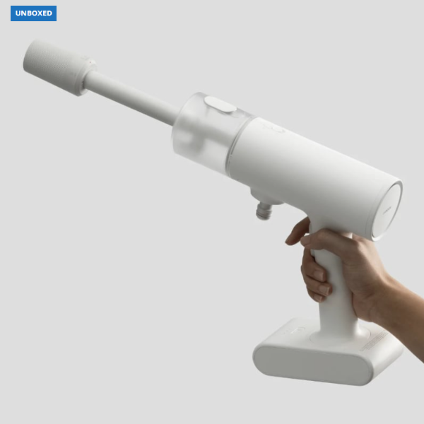 White handheld vacuum cleaner held by a hand on a light gray background