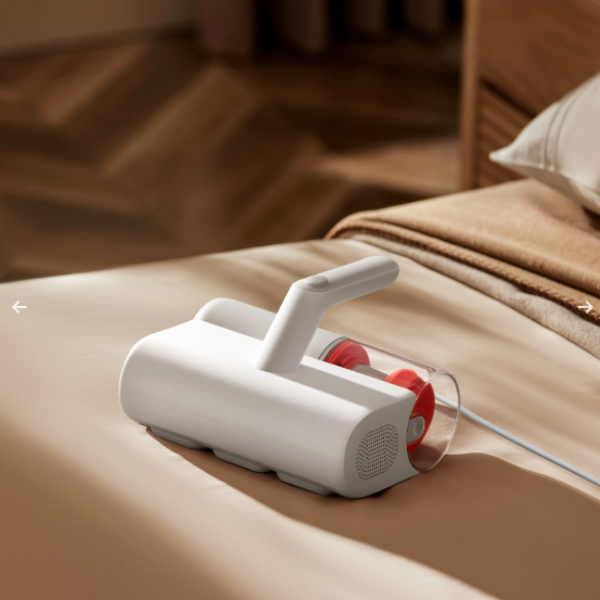 White handheld vacuum cleaner on a bed with a blurred background