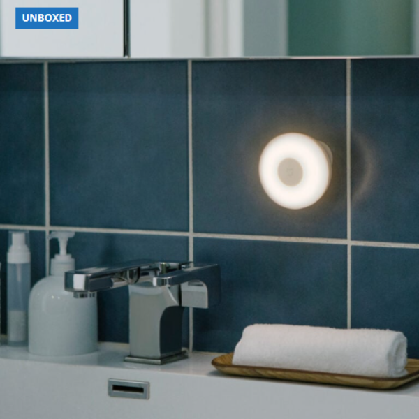Wall-mounted light fixture in a bathroom with blue tiles and a towel.