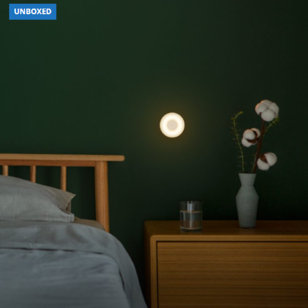 Wall-mounted light fixture in a bedroom with a bed and dresser.