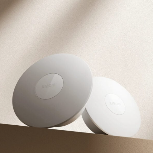 Two round white devices with a brand logo on a beige background