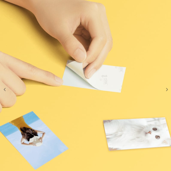 Hand applying a sticker to a photo on a yellow background