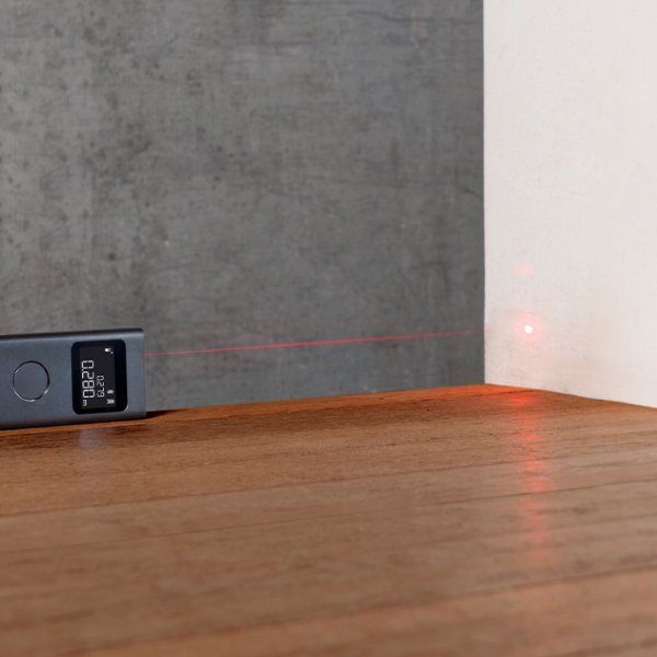 Laser level on a wooden surface with a concrete wall in the background