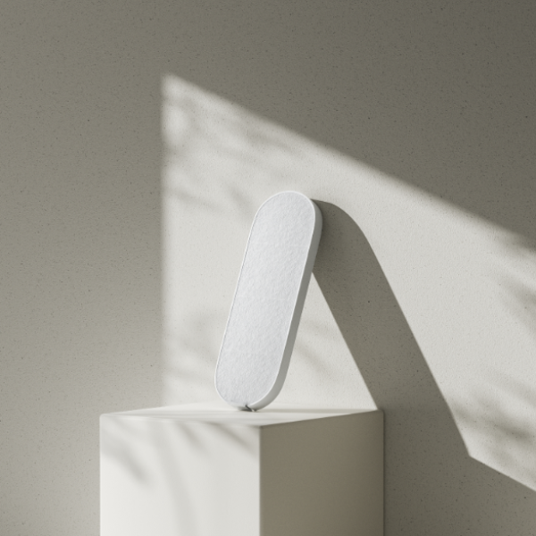 White cylindrical object on a white pedestal against a beige wall with soft shadows.