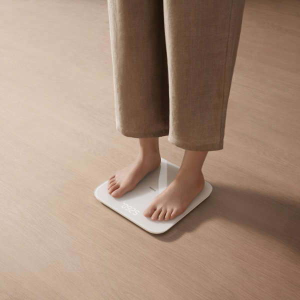 Person standing on a white digital scale on a wooden floor