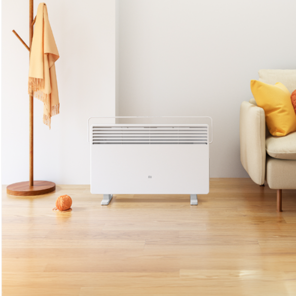 Convection heater on a wooden floor with a coat rack and sofa in the background
