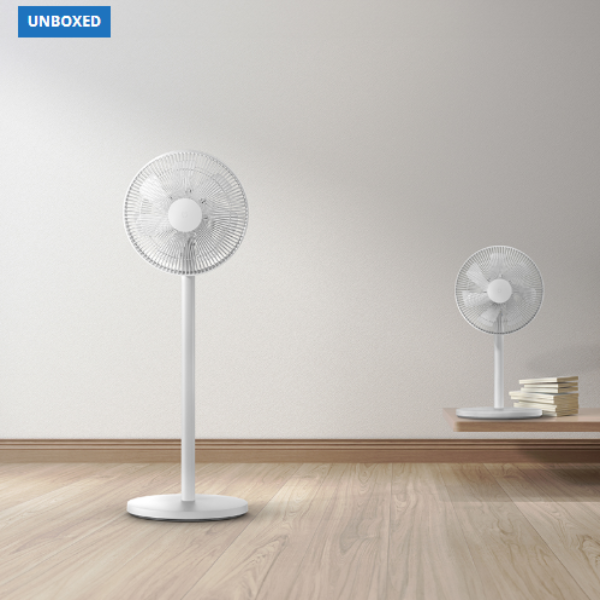 Two white standing fans on a wooden floor with a plain wall background.