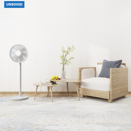 Modern living room with a floor fan, small table, and sofa against a white wall.