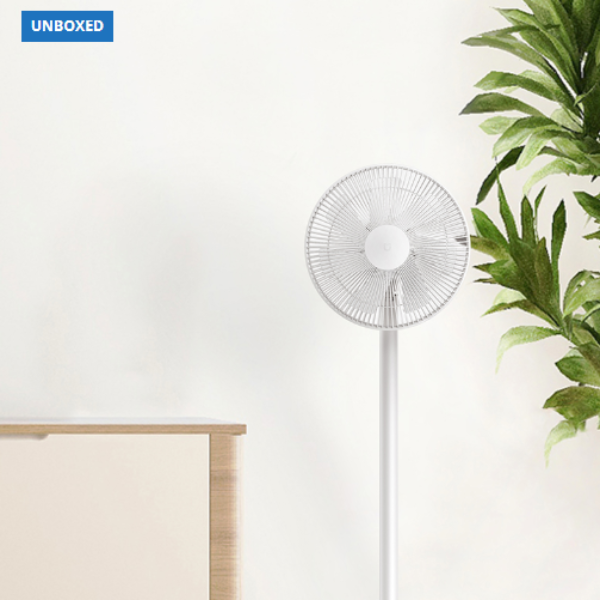 White floor fan on a white background with a plant to the right