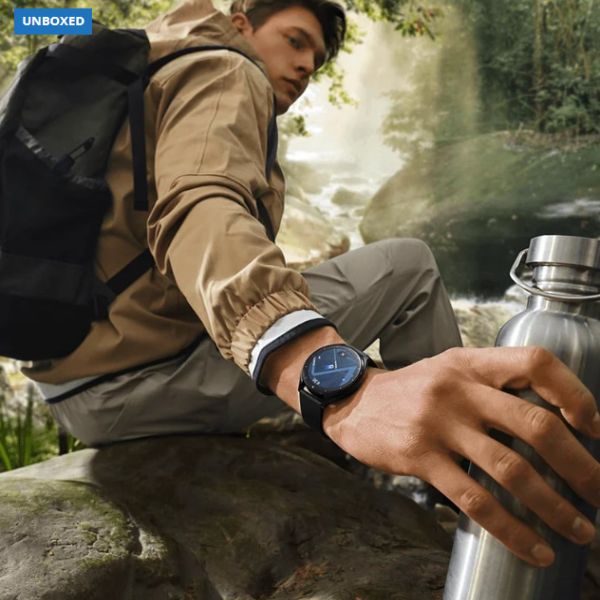 Man in outdoor setting with water bottle and watch, 'UNBOXED' label visible