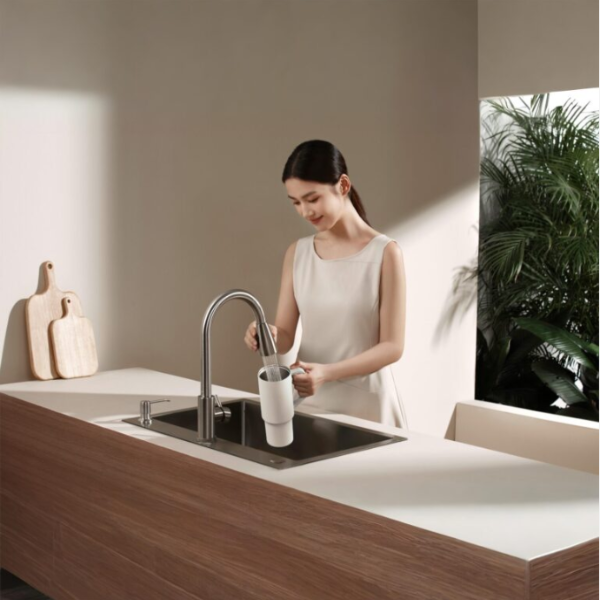 Woman using a faucet in a modern kitchen with a neutral color scheme.