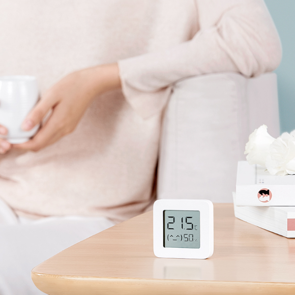 Digital thermometer on a table with a blurred person holding a cup in the background