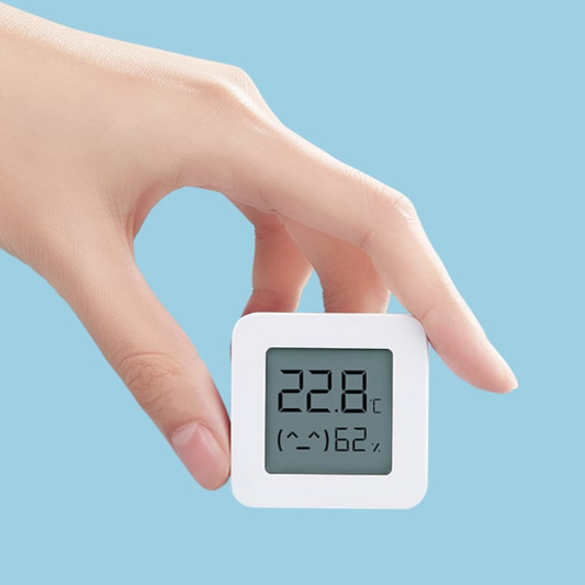 Digital thermometer held by a hand with a blue background