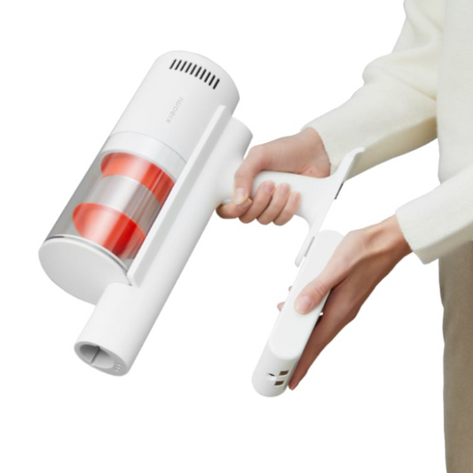 Hand holding a white handheld vacuum cleaner with red interior on a white background