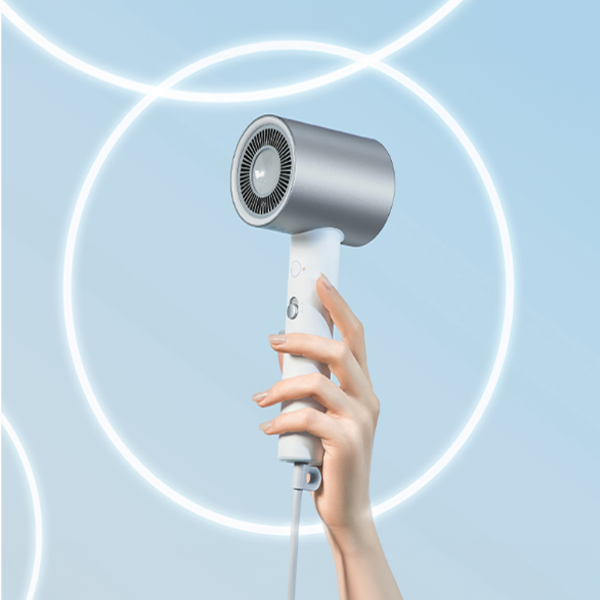 Hand holding a white and gray hair dryer against a light blue background