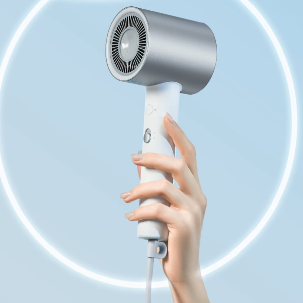 Hand holding a white handheld hair dryer with a blue circular background