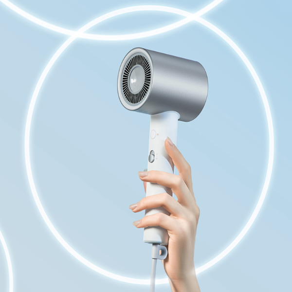 Hand holding a white and gray handheld hair dryer against a light blue background