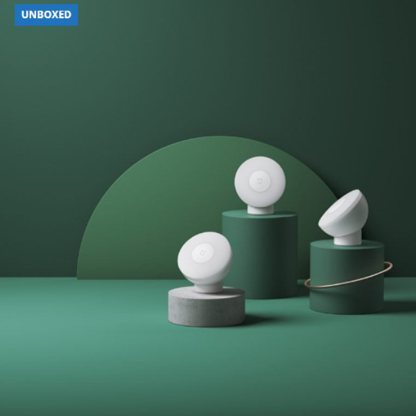 Three white spherical objects on green cylindrical stands against a green background with 'UNBOXED' branding.