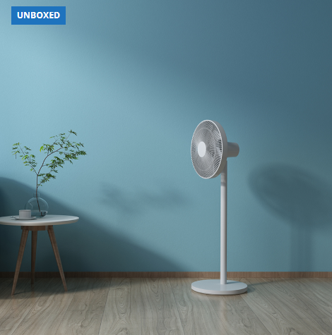 White standing fan on a wooden floor with a blue wall background
