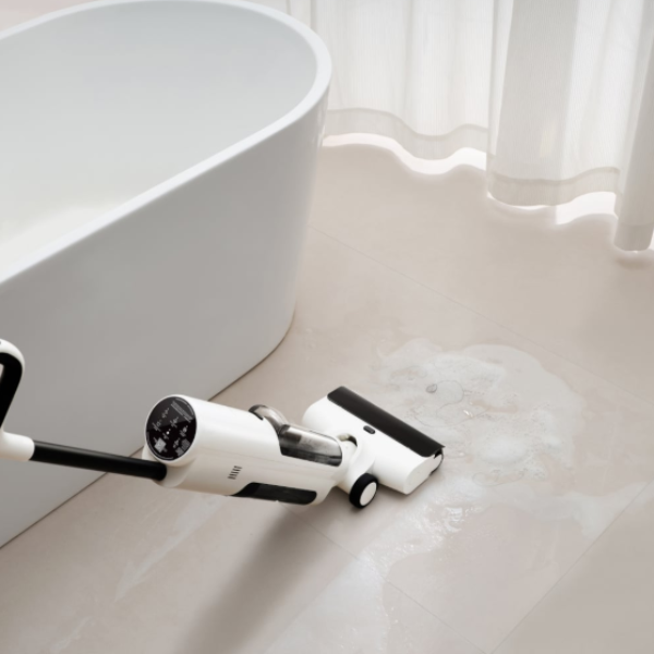 White and black cleaning tool on a tiled floor with a bathtub in the background